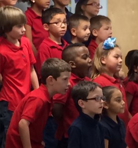 1st and 2nd grade students watch Ms. Dokken intently as they sing. 